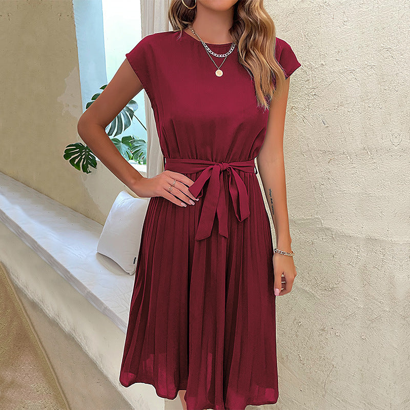 Model in pleated short-sleeve dress walking near ocean waves